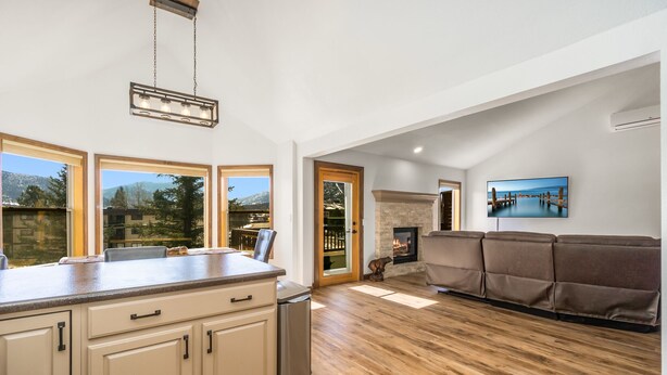 A spacious living area with a fireplace, wooden flooring, and a large window offering a view of the outdoors. - Spacious Family Getaway, King Beds, Hot Tub, RMNP (Estes Park)