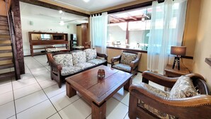 A spacious living room with a sofa set, a wooden coffee table, and a dining area with chairs and a table. - Centro UP (Búzios)