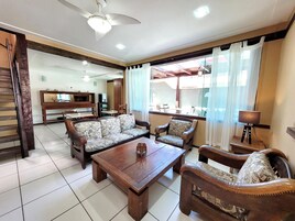 Amplia sala de estar con un juego de sofá, una mesa de centro de madera y un comedor con sillas y una mesa.