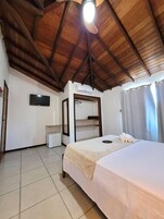 Un dormitorio con cama, televisor, armario y aire acondicionado.