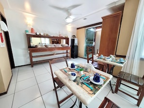 A dining area with a table set for two, a wooden cabinet, and a ceiling fan.
