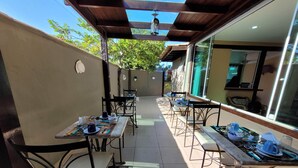 An outdoor patio area with tables and chairs, a pergola, and a view of the surrounding area. - Centro UP (Búzios)