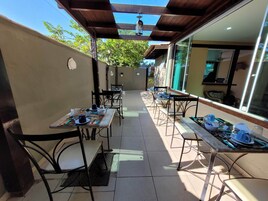 Un patio al aire libre con mesas y sillas, una pérgola y vistas del entorno.
