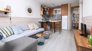 A compact living space with a sofa, a dining table, a kitchen area, and a small bar area. - Home2Book Cozy Helmut's Place Corralejo, Terrace (Corralejo)