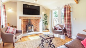 A cozy living room with a fireplace, comfortable seating, and a flat-screen TV. - The Croft (Thetford)