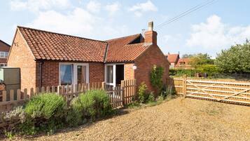 A brick house with a tiled roof, a wooden fence, and gravel driveway.