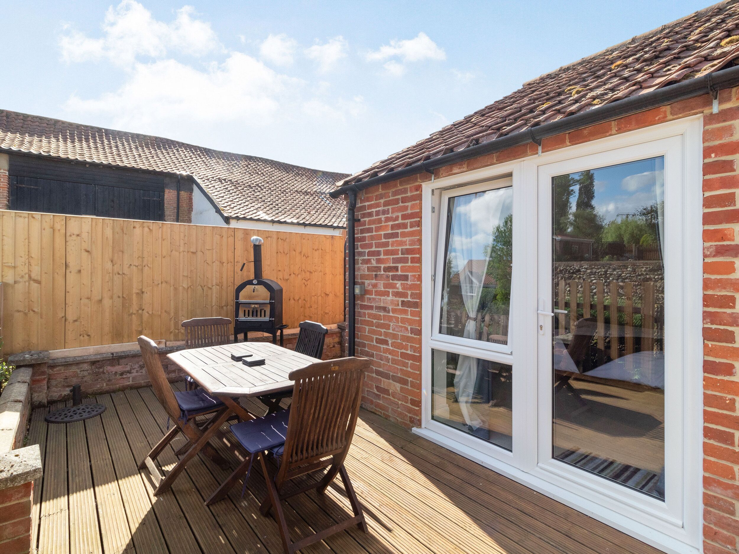 A patio with a table and chairs, a brick wall, and a wooden fence.