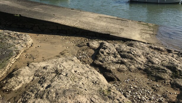 Un port où sont amarrés des bateaux, un bâtiment qui ressemble à un château et une côte rocheuse.