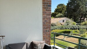 Un espace extérieur aménagé avec des meubles en osier, une table avec des boissons et une vue sur un jardin.