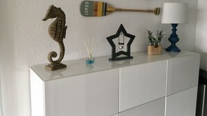 Un meuble blanc contenant des objets décoratifs, notamment une pagaie en bois, une lanterne en forme d’étoile, une sculpture d’hippocampe, un diffuseur de parfum à bâtonnets et une petite plante dans un coffret en bois.
