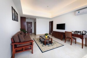 A living room with a sofa, coffee table, TV, and dining area. - Tongfa Hot Spring Hotel (Wanning)