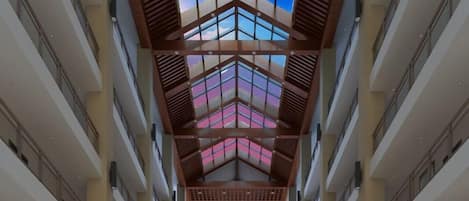 A corridor with a skylight and a view of a pink sky through the windows.