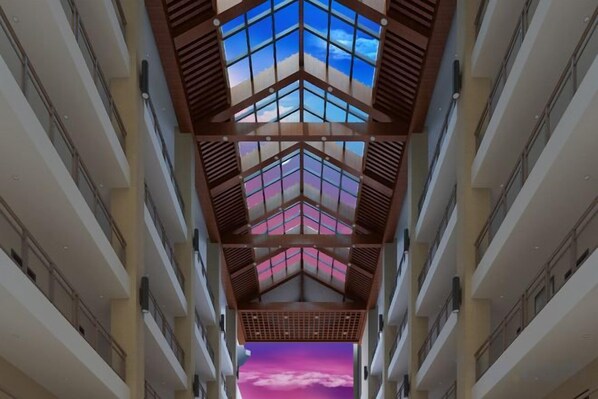 A corridor with a skylight and a view of a pink sky through the windows.