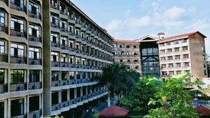 A multi-story hotel with balconies, a pool area, and lush greenery. - Tongfa Hot Spring Hotel (Wanning)