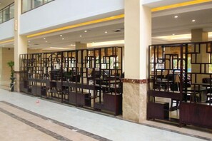 A hotel lobby with a seating area, a reception desk, and a decorative partition.