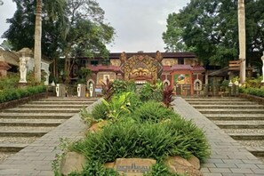 A traditional building with a central entrance, steps leading up to it, and a garden area in the foreground.