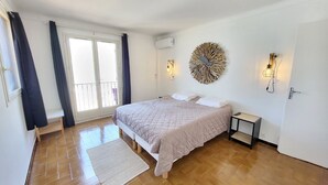 A bedroom with a bed, a small bedside table, a wall-mounted light fixture, and a decorative wall piece. - Apartment rental Propriano (Propriano)