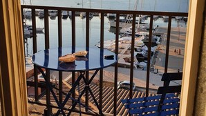 A balcony with a round table and chairs, overlooking a marina with boats and a hilly landscape. - Apartment rental Propriano (Propriano)