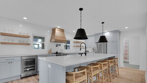 Una cucina moderna con una grande isola, sgabelli da bar e un forno integrato.