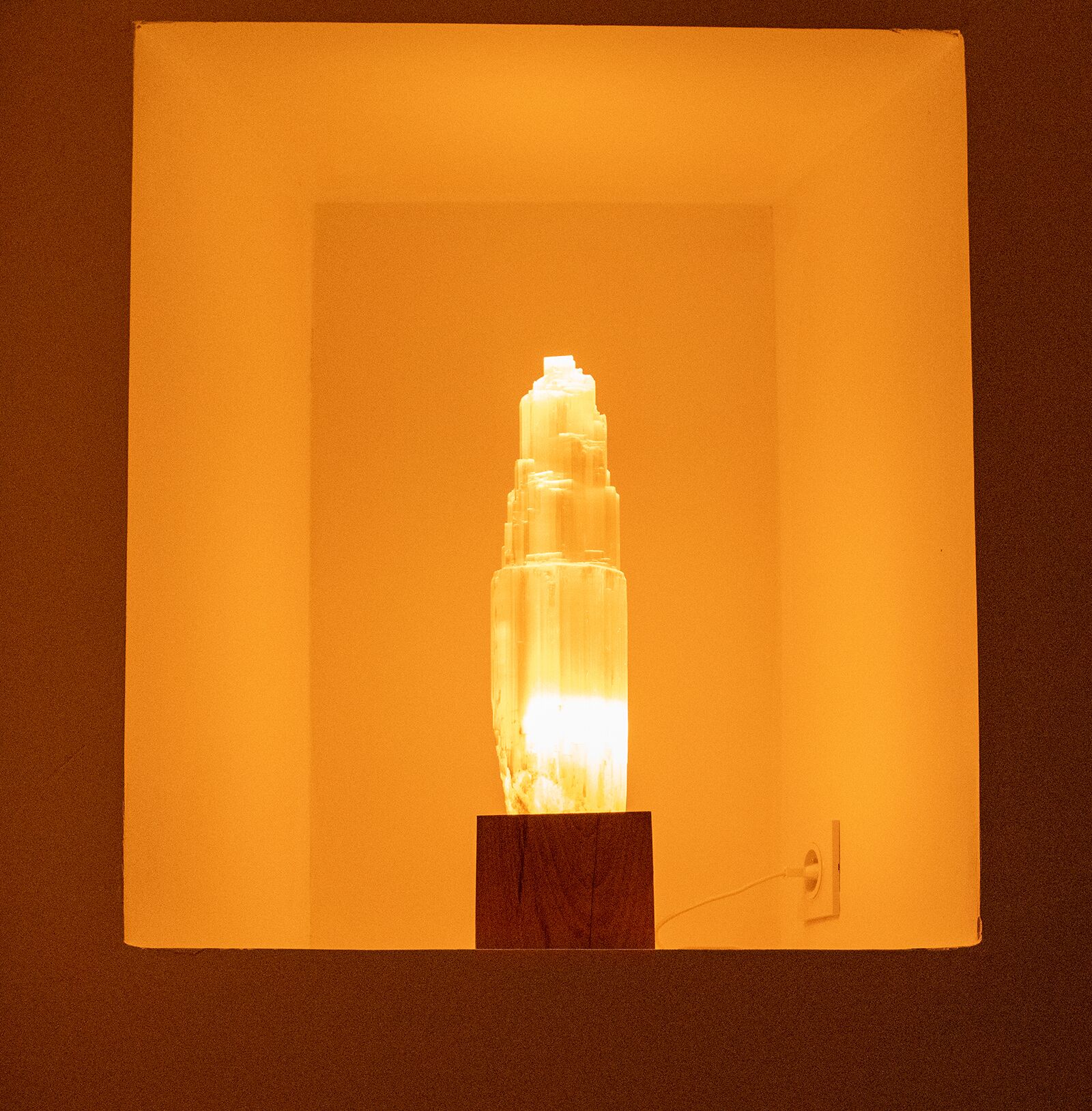 Eine Glaskulptur mit integrierter Beleuchtung, die auf einem Sockel platziert ist.