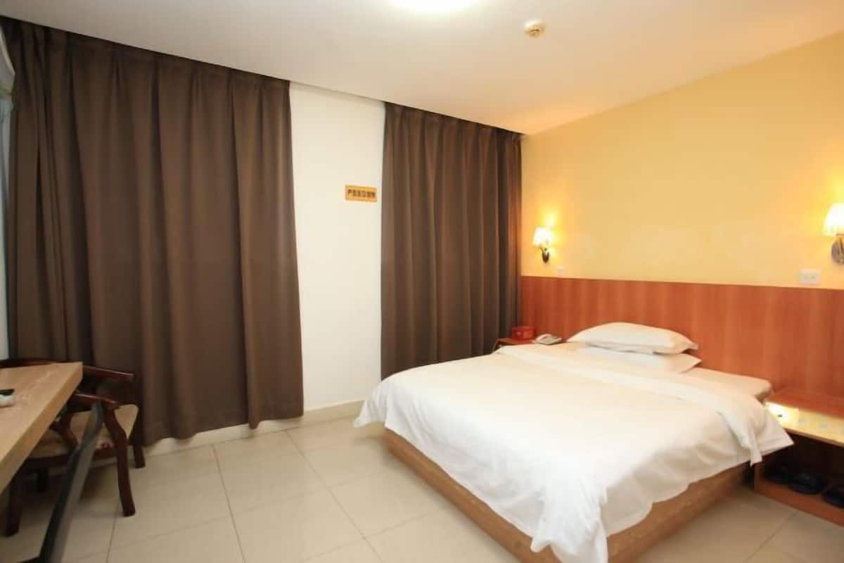 A hotel room with a bed, a desk, and curtains.