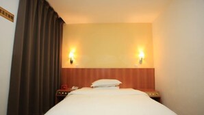A hotel room with a bed, two wall-mounted lamps, a nightstand, a telephone, and a curtain. - Dongfang Hotel (Shenzhen)