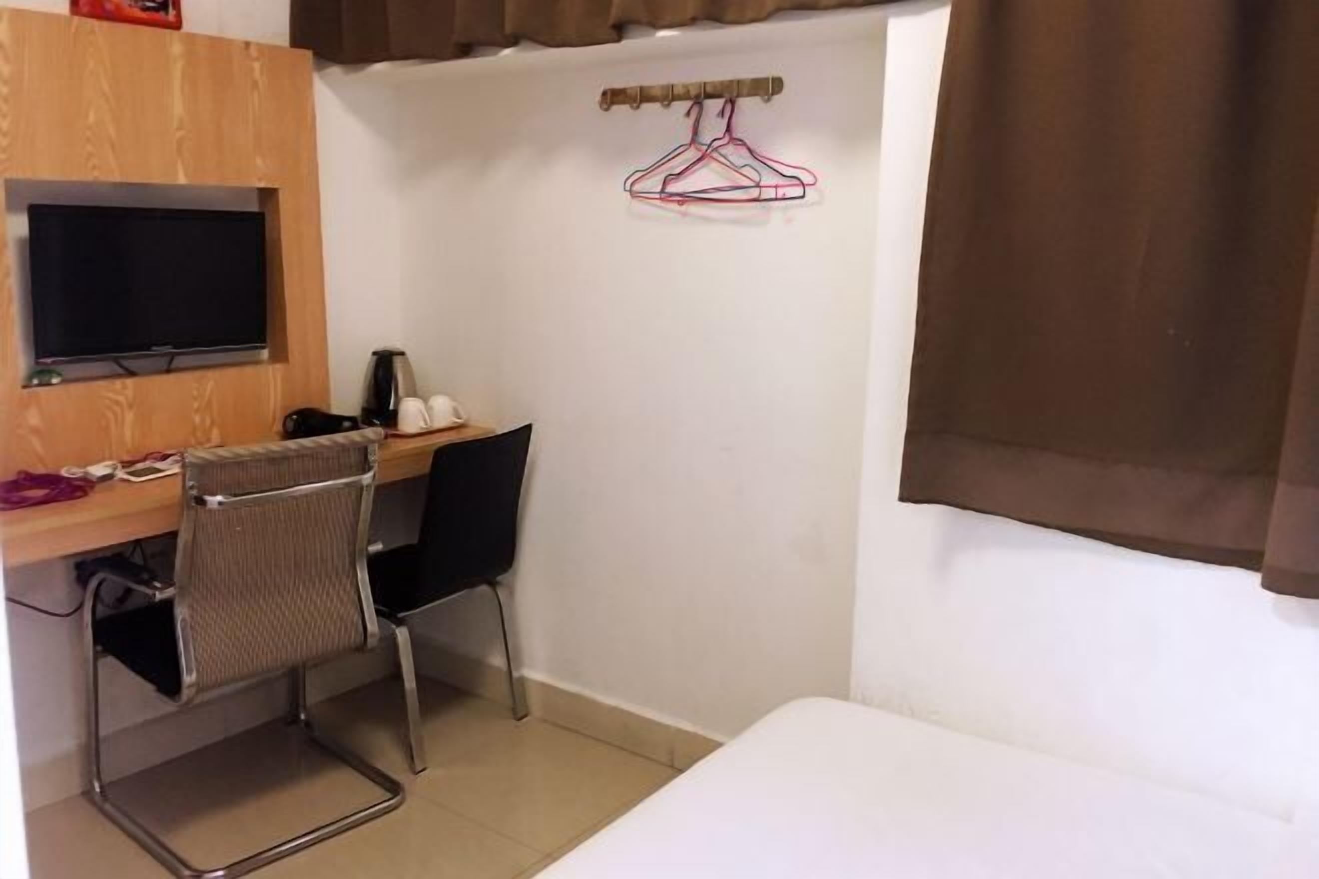 A small room with a desk, chair, TV, and a bed.