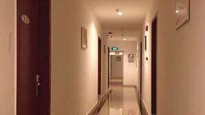 A hotel corridor with a wooden door, a glass railing, and a sign indicating the direction to the elevator. - Dongfang Hotel (Shenzhen)