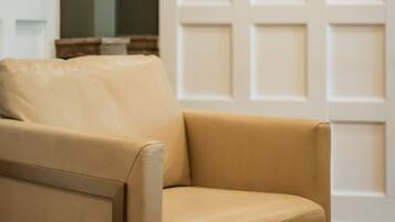 A beige leather chair in a room with a white door and a framed painting on the wall.