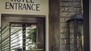 A hotel entrance with a sign, a door, and a lantern. - Marsh Hotel (New Orleans)