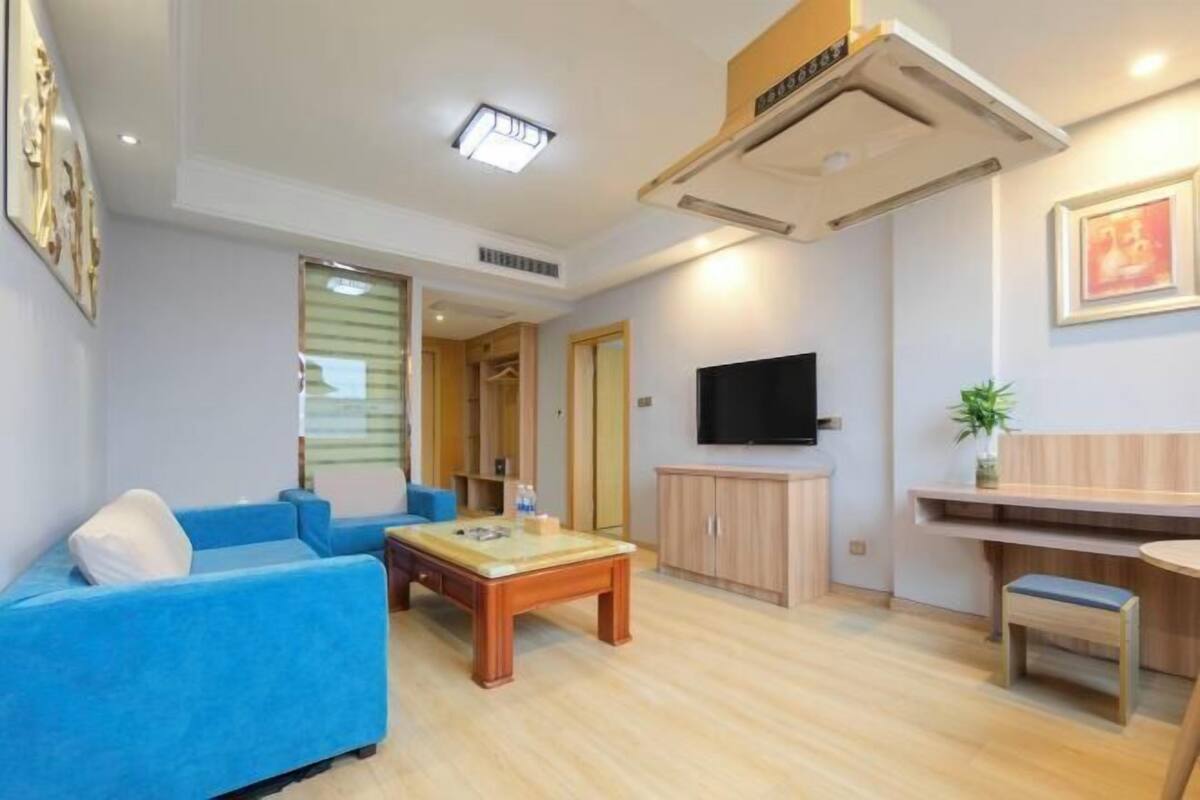 A modern living room with a blue sofa, wooden coffee table, and a TV mounted on the wall.