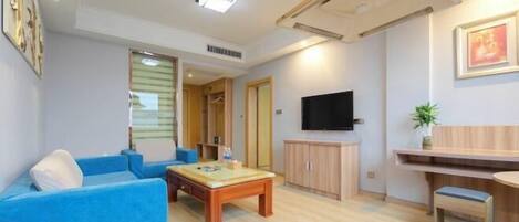 A modern living room with a blue sofa, wooden coffee table, and a TV mounted on the wall.