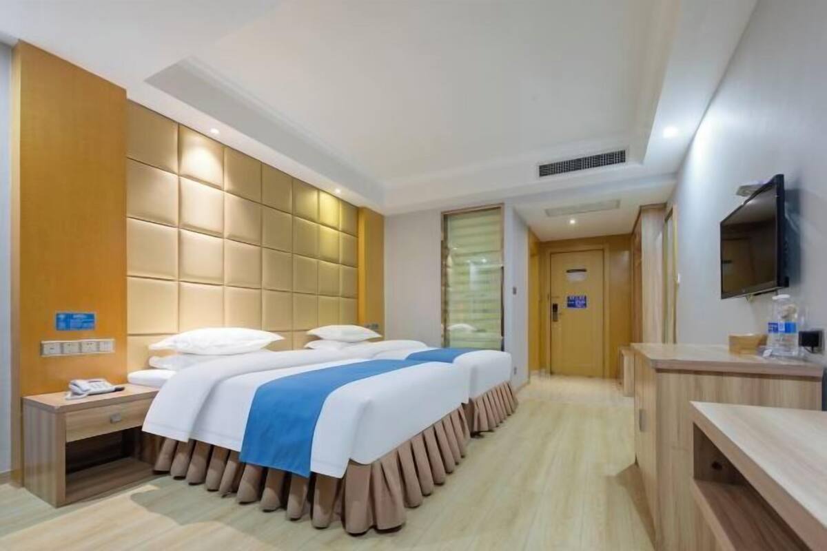 A hotel room with a large bed, bedside tables, a TV, and a wooden desk.
