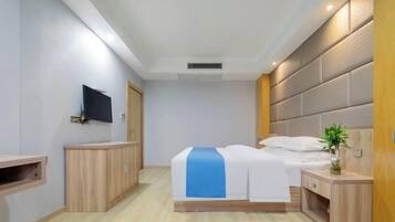 A hotel room with a bed, bedside tables, a TV mounted on the wall, and a wooden cabinet.