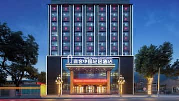 Un hotel de varios pisos con una entrada destacada y señalización iluminada.