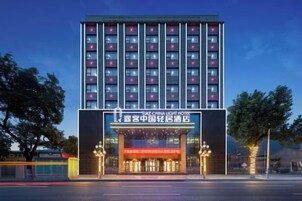 Un hotel de varios pisos con una entrada destacada y señalización iluminada.