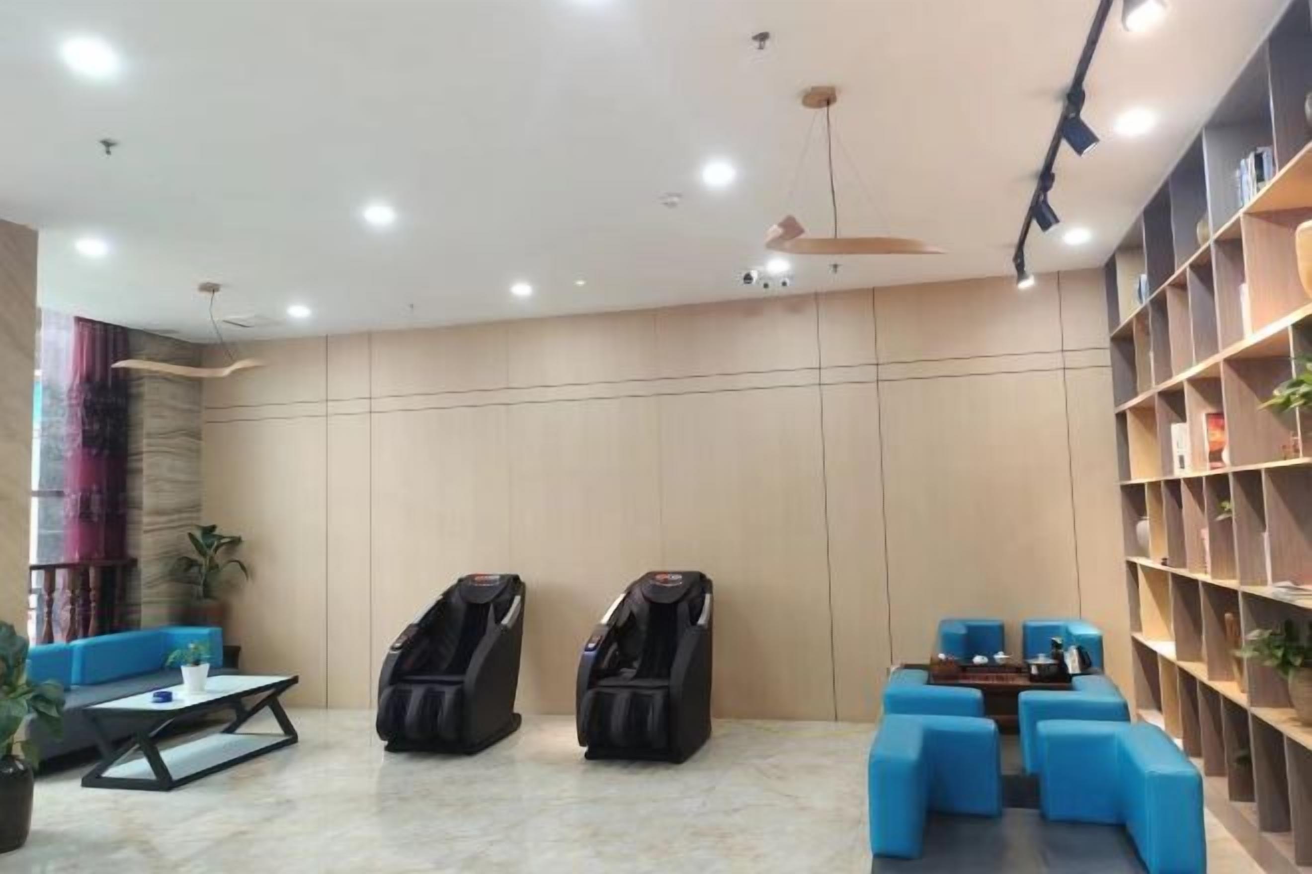 A room with massage chairs, a sofa, a coffee table, and a bookshelf.
