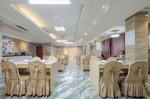 Un salón de conferencias con mesas y sillas, una zona de cocina y vistas a la ciudad.