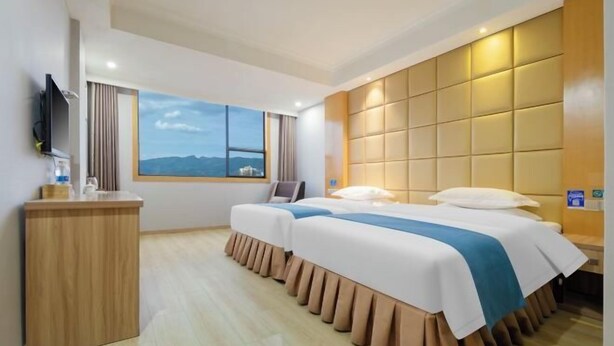 A hotel room with a large bed, a TV on a wooden cabinet, and a window with a mountain view. - Tuke China Light Residence Hotel (Shiyan Wudangshan Airport Branch) (Shiyan)