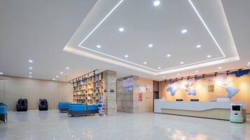 Un hall de hotel con mostrador de recepción, zona de estar y estantería.