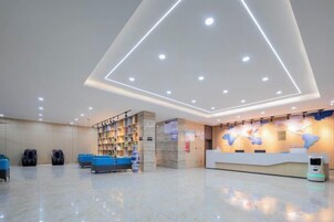 Un hall de hotel con mostrador de recepción, zona de estar y estantería.