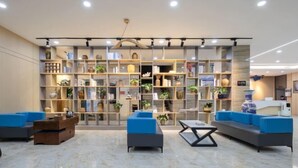 A modern lobby with a large bookshelf, blue seating, and a reception desk. - Tuke China Light Residence Hotel (Shiyan Wudangshan Airport Branch) (Shiyan)