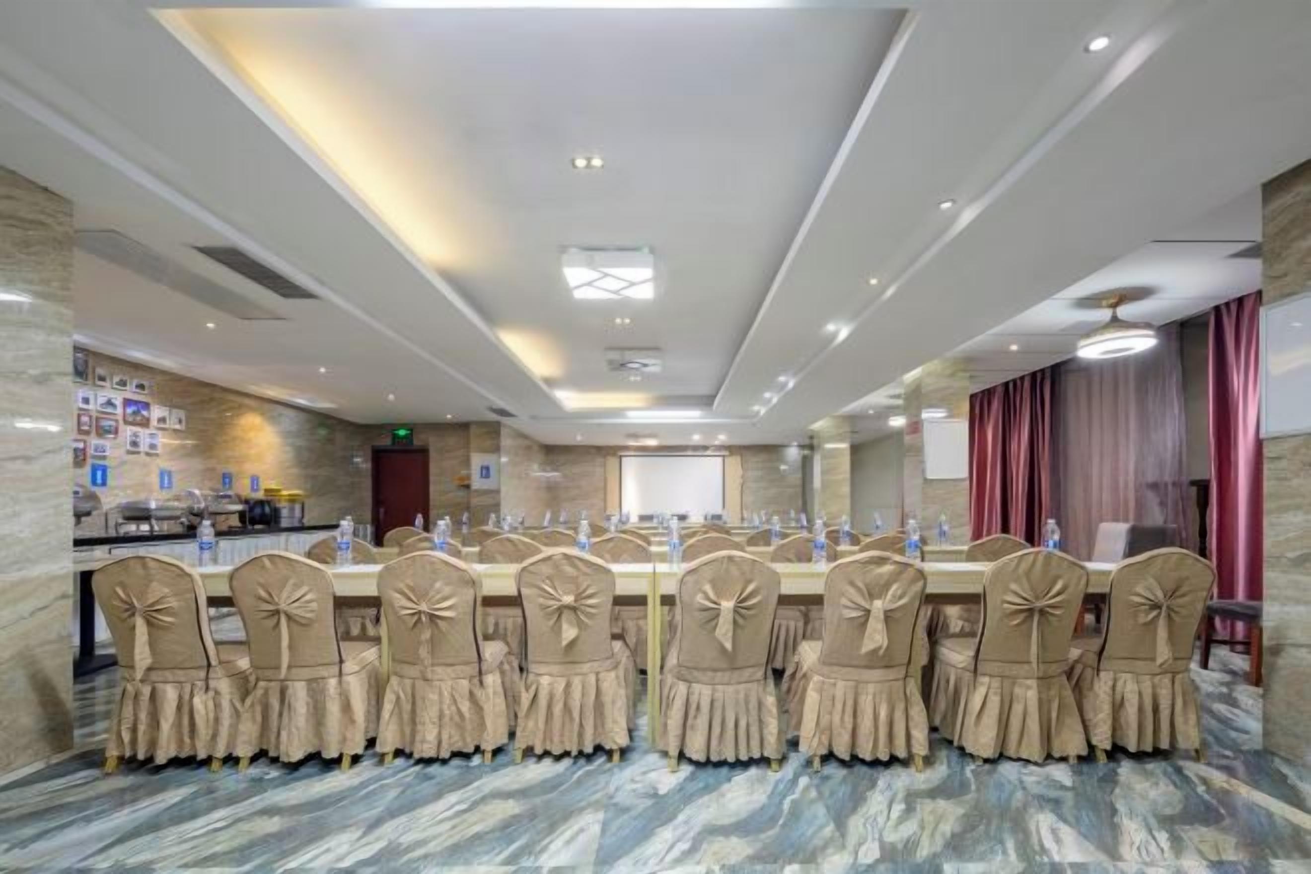 A conference room with a long table, chairs, and a projector screen.