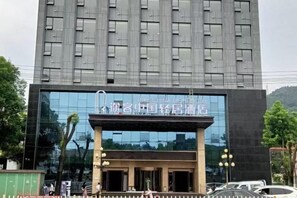 Um edifício moderno com fachada de vidro refletivo e uma placa indicando que é um hotel.
