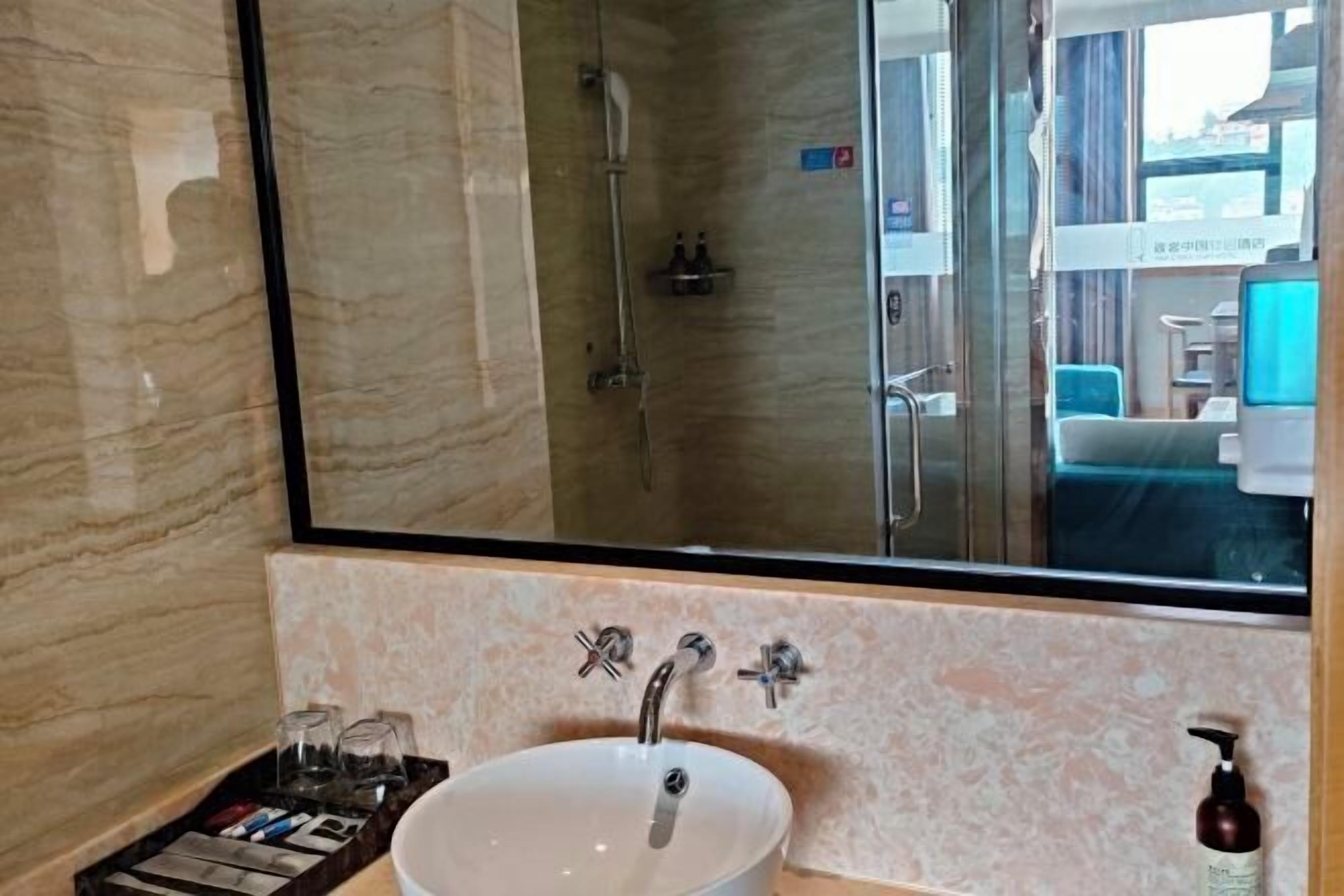 A modern bathroom with a large mirror, a vessel sink, and a shower area.