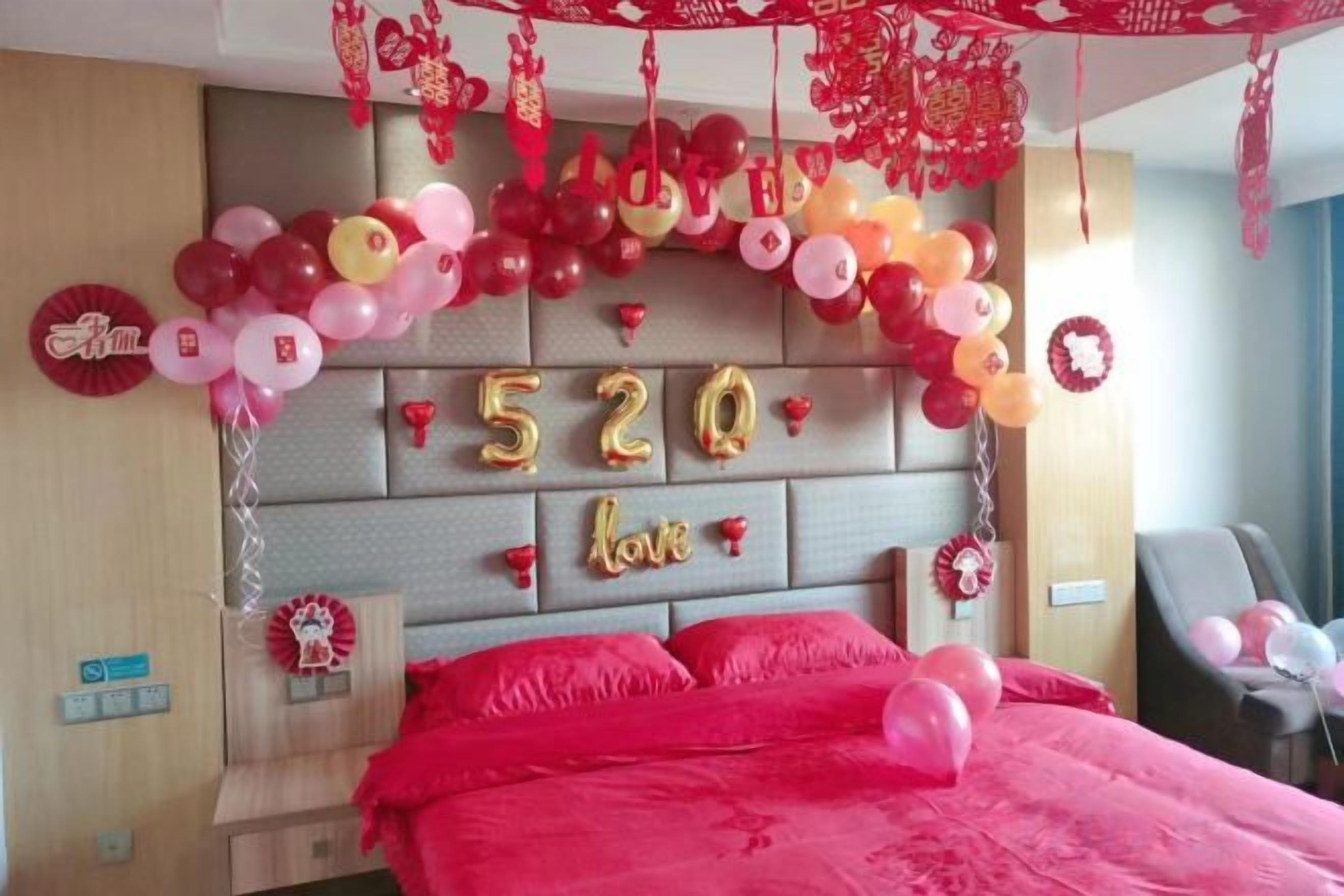 Een hotelkamer met een bed, een hoofdeinde versierd met ballonnen en een wandklok.