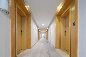 Un pasillo de hotel con puertas de madera, piso alfombrado e iluminación en el techo.