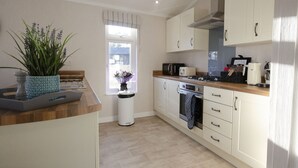 A modern kitchen with white cabinets, a stove, oven, and a window with curtains.