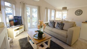 A living room with a sofa, TV, coffee table, and a view of the outdoors.