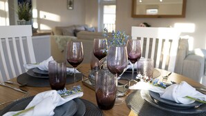 A dining table set with plates, glasses, and cutlery, with a sofa and a mirror in the background.